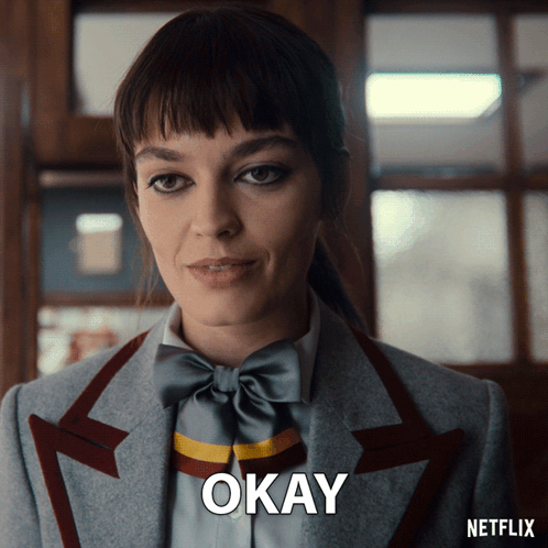 A Woman In A Suit And Bow Tie Says Okay On A Netflix Ad GIF
