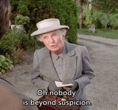 A Woman In A Suit And Hat Says Oh Nobody Is Beyond Suspicion While Holding A Briefcase GIF