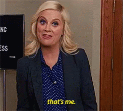 A Woman In A Suit And Polka Dot Shirt Is Standing In Front Of A Sign That Says `` That 'S Me '' . GIF