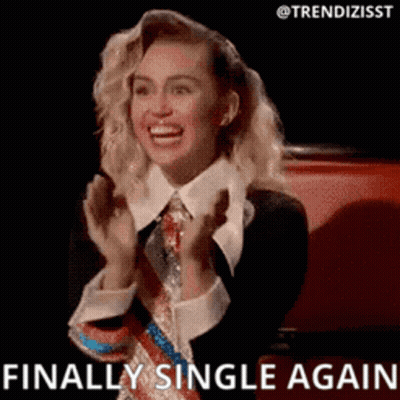 A Woman In A Suit And Tie Is Smiling And Clapping Her Hands . GIF