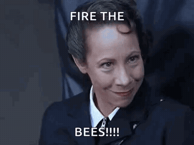 A Woman In A Suit And Tie Is Smiling With The Words `` Fire The Bees '' Written Above Her . GIF