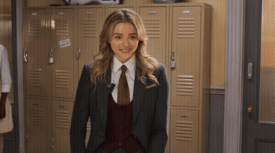 A Woman In A Suit And Tie Stands In Front Of A Row Of Lockers With A Sticker That Says Cold GIF