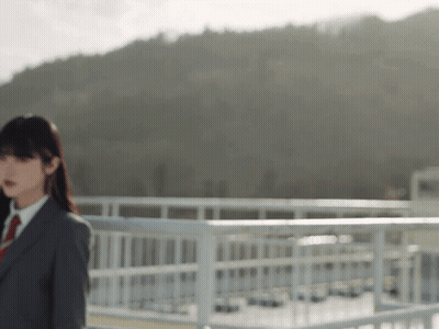 A Woman In A Suit And Tie Stands On A Bridge GIF