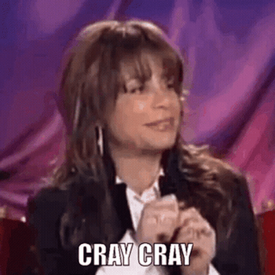 A Woman In A Suit And White Shirt Is Sitting In Front Of A Purple Curtain And Says `` Cray Cray '' . GIF