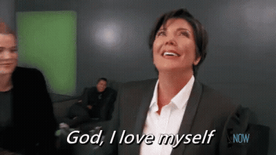 A Woman In A Suit And White Shirt Is Smiling And Saying God , I Love Myself . GIF