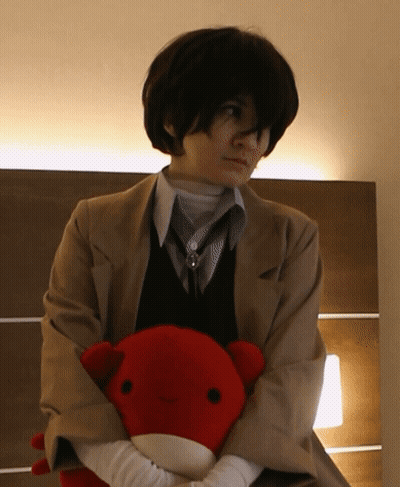 A Woman In A Suit Holds A Stuffed Animal In Her Hands GIF