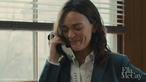 A Woman In A Suit Is Crying While Talking On A Phone With Ella Mccay Written In The Corner GIF