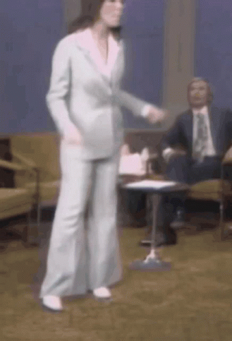 A Woman In A Suit Is Dancing In Front Of A Group Of Men GIF