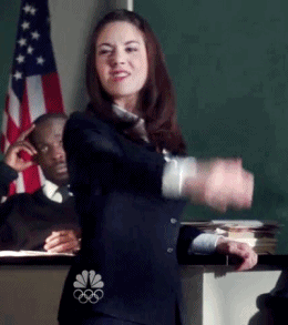 A Woman In A Suit Is Dancing In Front Of A Nbc Logo On The Back Of Her Jacket GIF
