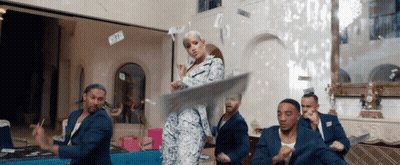 A Woman In A Suit Is Dancing With A Group Of Men GIF