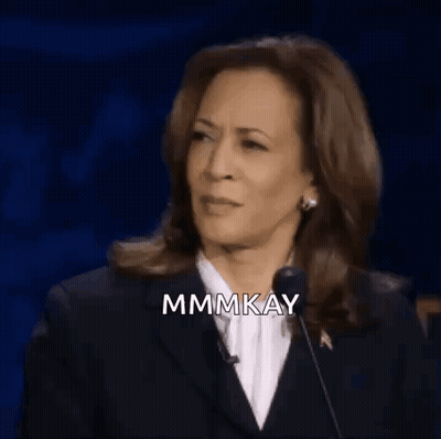 A Woman In A Suit Is Giving A Speech In Front Of A Microphone And Smiling . GIF