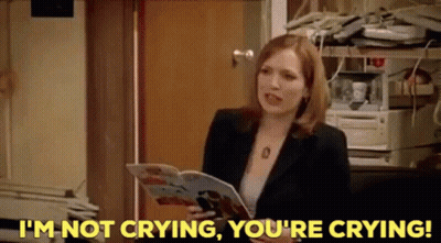 A Woman In A Suit Is Holding A Magazine And Saying I 'M Not Crying , You 'Re Crying . GIF
