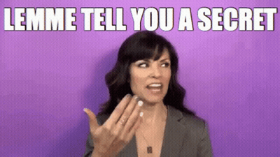 A Woman In A Suit Is Making A Funny Face And Says Lemme Tell You A Secret . GIF
