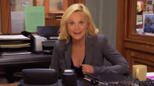 A Woman In A Suit Is Sitting At A Desk With A Printer . GIF