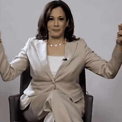 A Woman In A Suit Is Sitting In A Chair With Her Arms Outstretched GIF