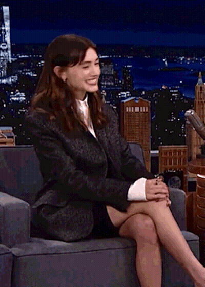 A Woman In A Suit Is Sitting In A Chair With Her Legs Crossed . GIF