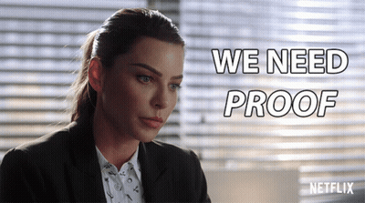 A Woman In A Suit Is Sitting In Front Of A Netflix Sign GIF