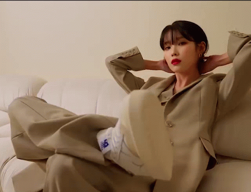 A Woman In A Suit Is Sitting On A Couch With Her Feet Up GIF