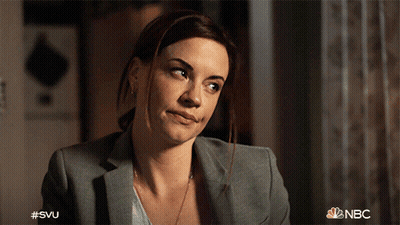 A Woman In A Suit Is Smiling With The Nbc Logo In The Background GIF