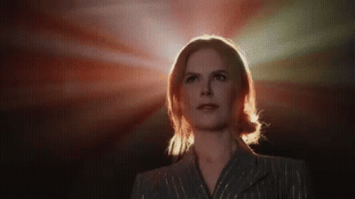 A Woman In A Suit Is Standing In Front Of A Red Light And Looking Up . GIF