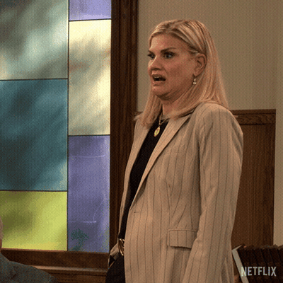 A Woman In A Suit Is Standing In Front Of A Stained Glass Window With A Netflix Logo On The Bottom GIF