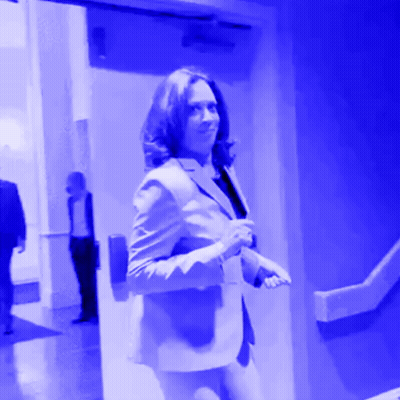 A Woman In A Suit Is Walking Through A Blue Door GIF