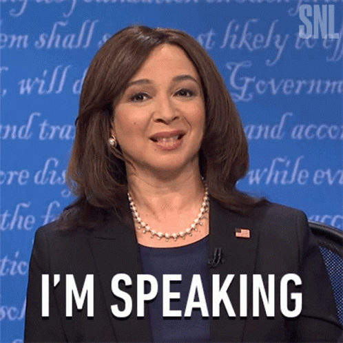 A Woman In A Suit Says I 'M Speaking In Front Of A Blue Background GIF