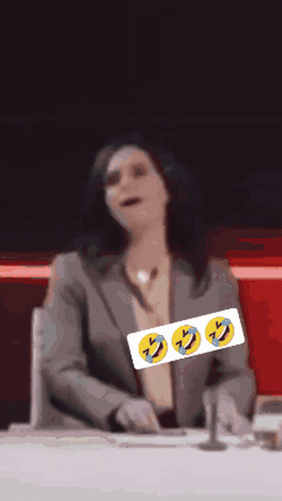 A Woman In A Suit Sits At A Desk With Three Smiley Faces On It GIF