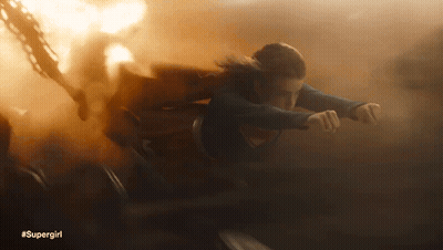 A Woman In A Supergirl Costume Is Flying Through Smoke GIF