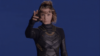 A Woman In A Superhero Costume Is Pointing At Something GIF