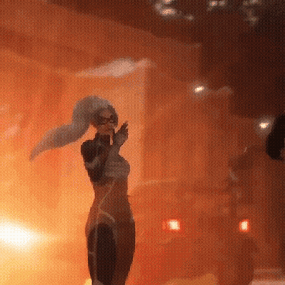 A Woman In A Superhero Outfit Is Standing In Front Of A Fire GIF