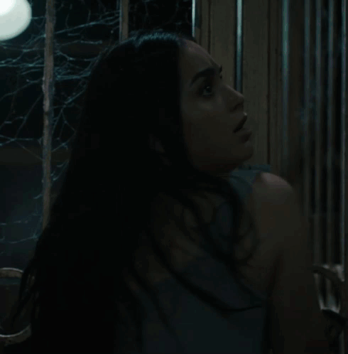A Woman In A Superman Costume Is Standing In The Dark GIF