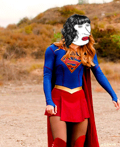 A Woman In A Superman Costume With A White Face On Her Face GIF