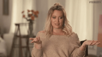 A Woman In A Sweater Is Shrugging Her Shoulders And Making A Funny Face . GIF