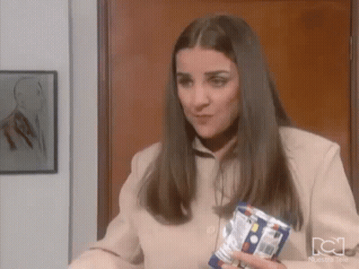 A Woman In A Tan Jacket Is Holding A Can Of Soda In Her Hand . GIF