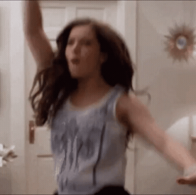 A Woman In A Tank Top Is Dancing With Her Arms Outstretched . GIF