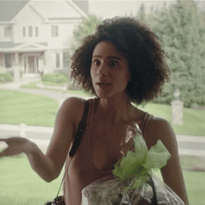 A Woman In A Tank Top Is Holding A Bag Of Grapes GIF