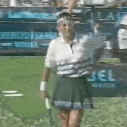 A Woman In A Tennis Skirt Is Holding A Tennis Racquet GIF
