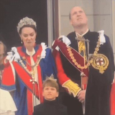 A Woman In A Tiara Is Standing Next To A Man In A Suit And A Boy In A Black Shirt . GIF