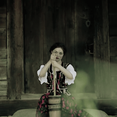 A Woman In A Traditional Costume Is Sitting On A Wooden Bucket GIF