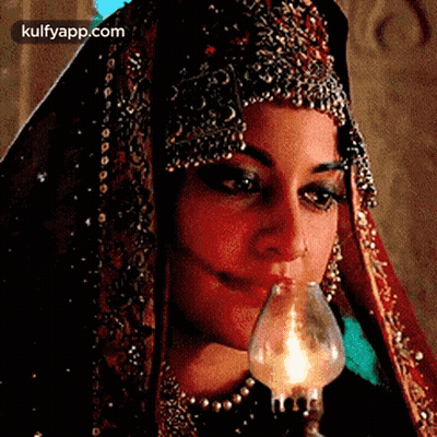 A Woman In A Traditional Dress Is Holding A Candle In Her Mouth . GIF