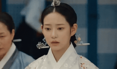 A Woman In A Traditional Korean Dress Is Standing In A Room . GIF