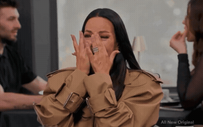 A Woman In A Trench Coat Covering Her Face With Her Hands And The Words All New Original On The Bottom GIF