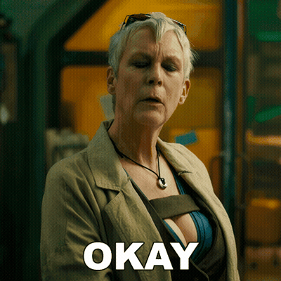 A Woman In A Trench Coat Has The Word Okay Written On Her Chest GIF