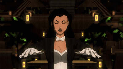 A Woman In A Tuxedo And White Gloves Stands With Her Arms Outstretched In A Dark Room GIF