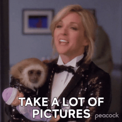 A Woman In A Tuxedo Is Holding A Baby Monkey And Says " Take A Lot Of Pictures " GIF