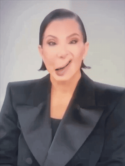 A Woman In A Tuxedo Is Making A Funny Face With Her Tongue Out . GIF