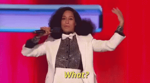 A Woman In A Tuxedo Is Singing Into A Microphone While Dancing On A Stage . GIF