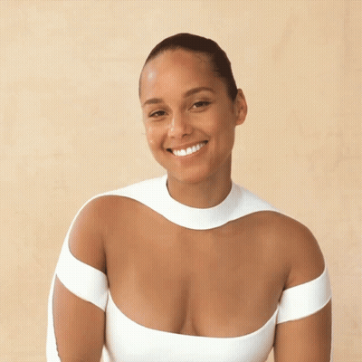 A Woman In A Very Plunging White Top Smiles GIF