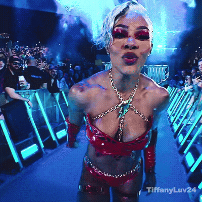 A Woman In A Very Revealing Outfit Is Standing In Front Of A Crowd With Tiffanyluv24 On The Bottom Right GIF